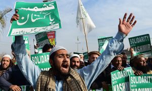 Pakistani citizens rallying with flags and banners in support of Kashmir